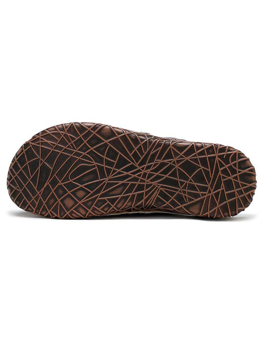 Sole view of floral slippers with brown lattice-pattern tread and dark upper edge