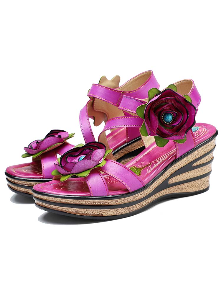 Pink wedge sandals with rose embellishments and cross straps on a cork-style sole