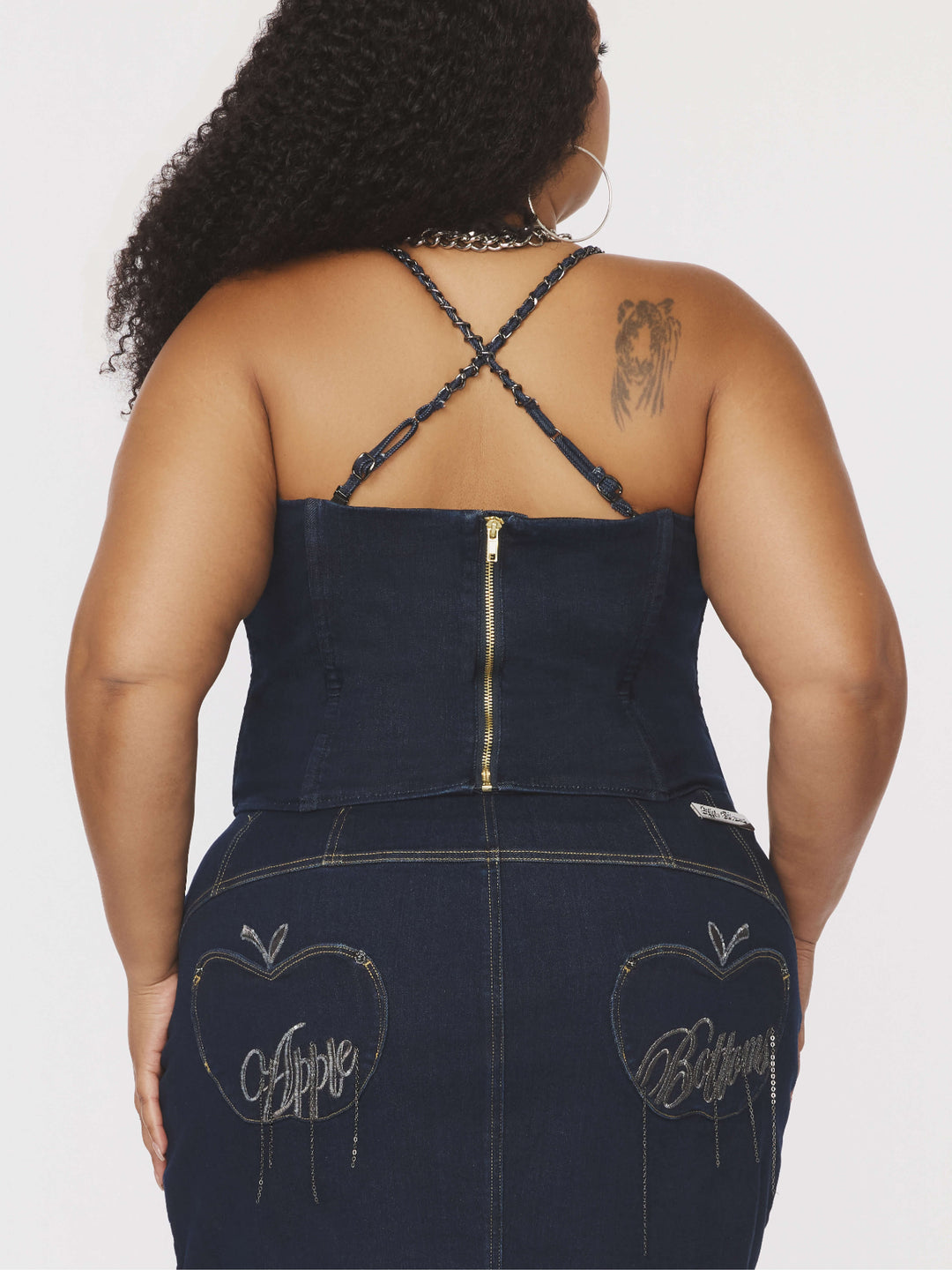 Espalda del bustier de mezclilla azul con tirantes de cadena cruzados y cierre frontal.