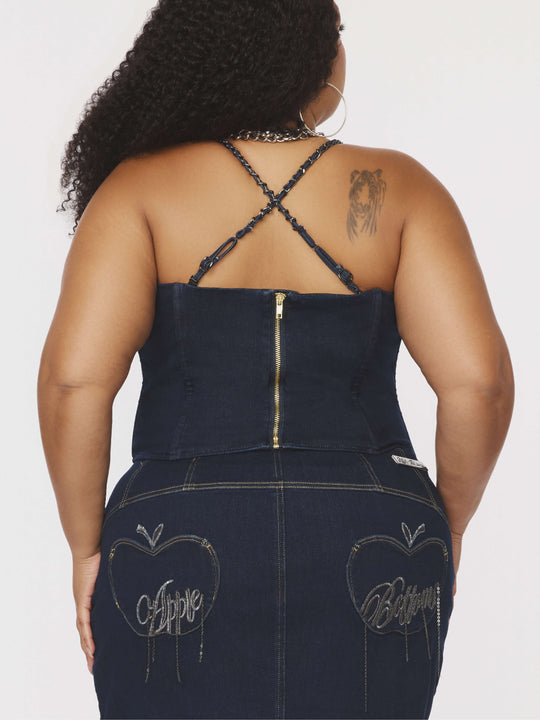 Espalda del bustier de mezclilla azul con tirantes de cadena cruzados y cierre frontal.