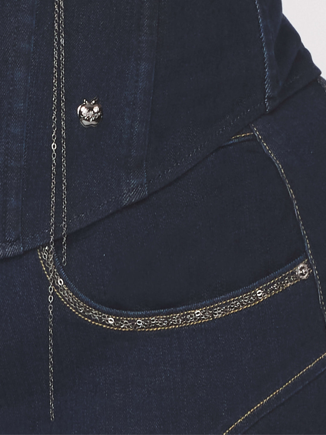 Detalle del bustier: borde con cadena y botón metálico en mezclilla azul.