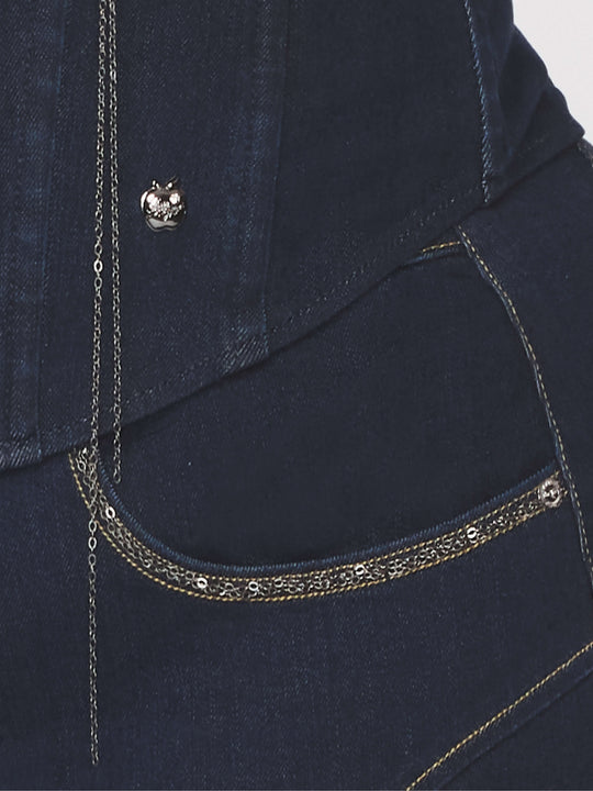 Detalle del bustier: borde con cadena y botón metálico en mezclilla azul.