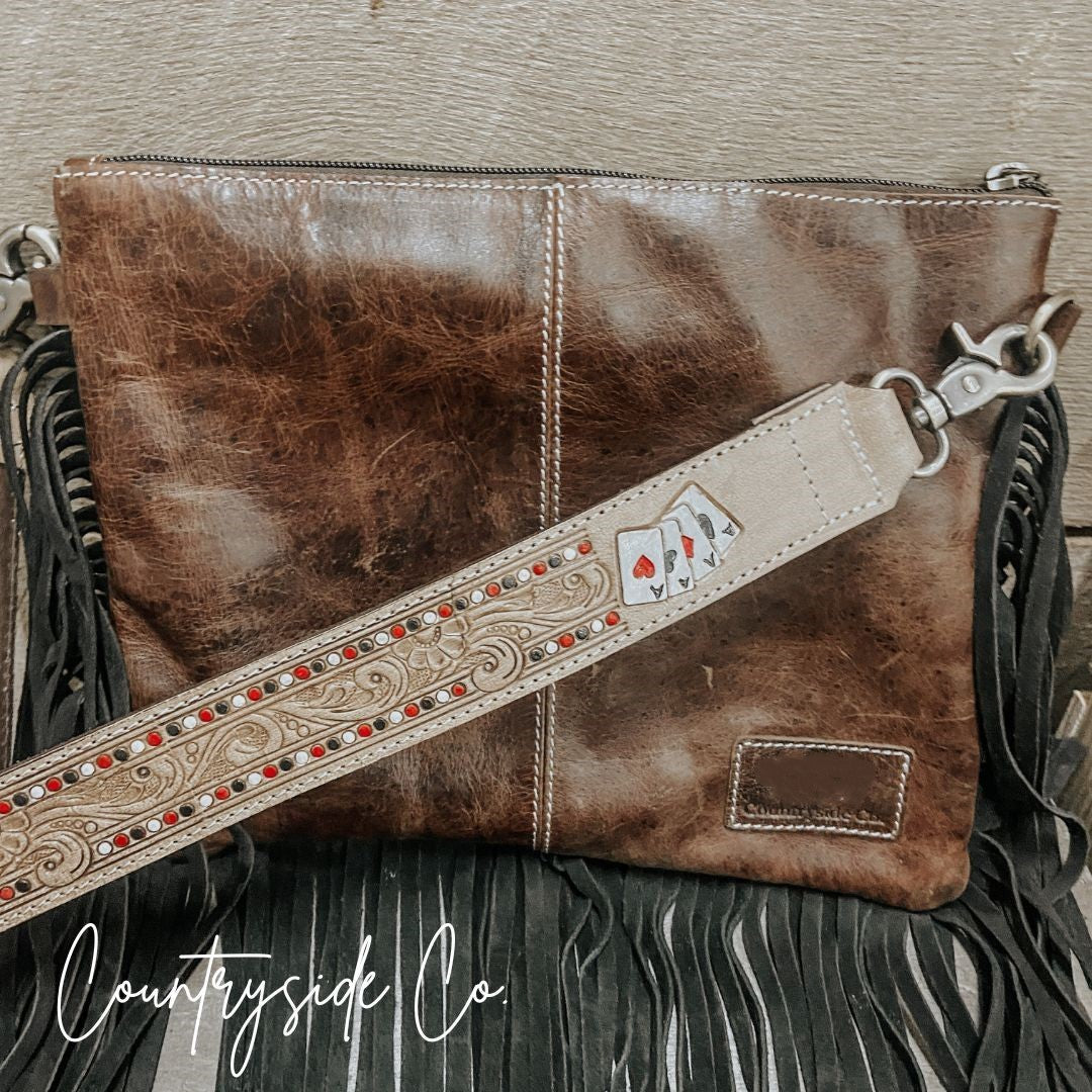 Brown cowhide clutch purse with leather strap and long black fringe tassels