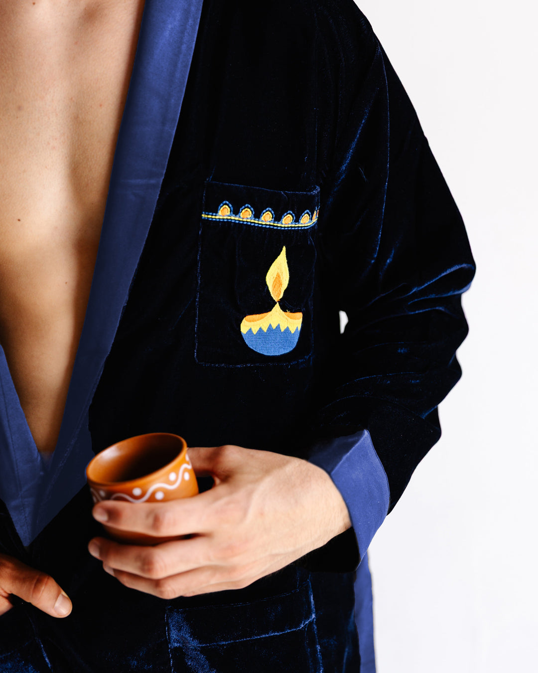 Navy velvet robe detail with light-blue satin cuff and candle pocket motif