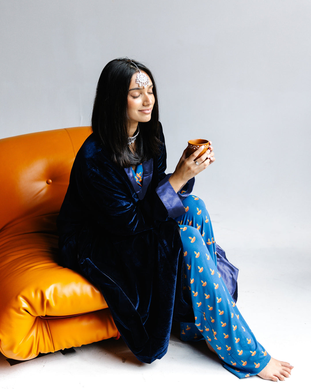 Adult robe set: navy velvet robe with patterned light-blue pants, holding a cup
