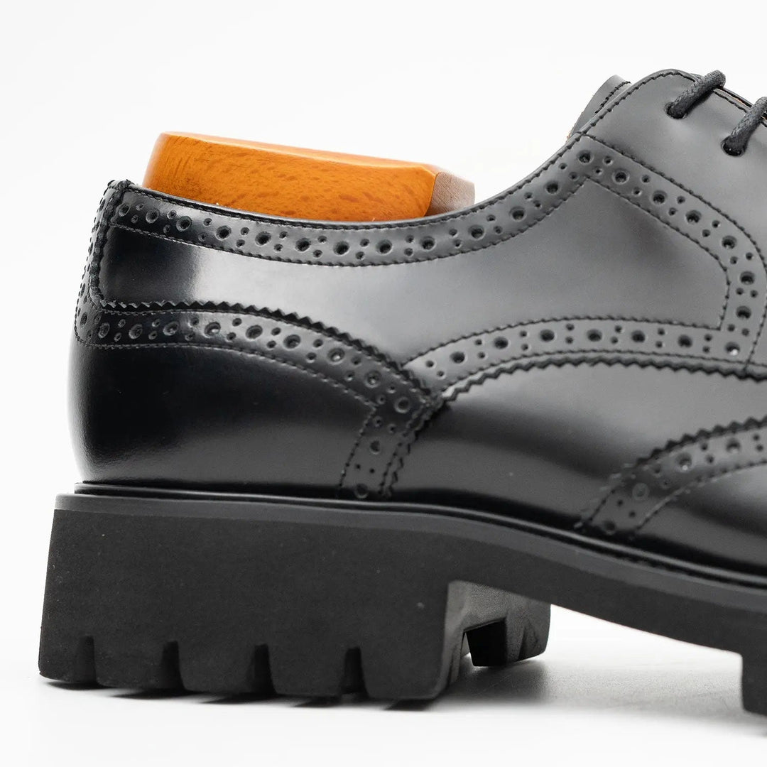 Close-up of black derby brogue upper with perforated trim and lace eyelets