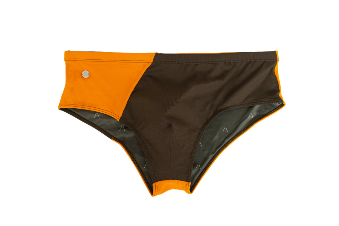 Two-tone swim brief: orange side with small round logo button, dark other side