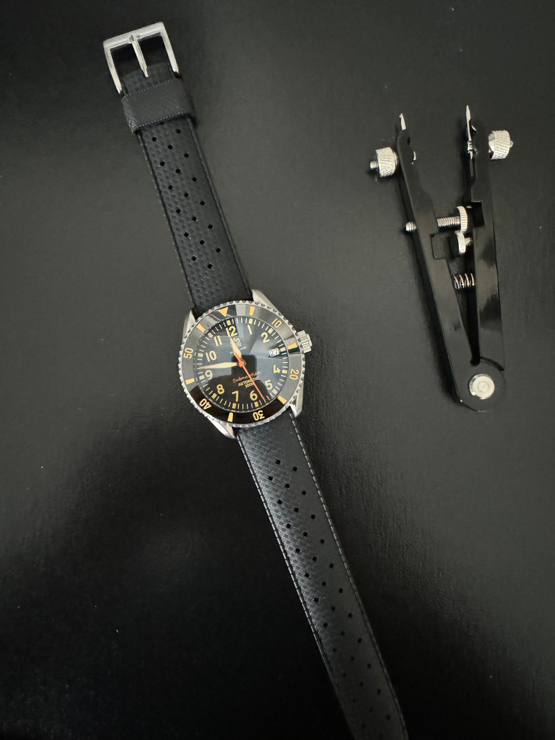 Tropic Bands watch with black perforated strap and silver buckle, dark dial