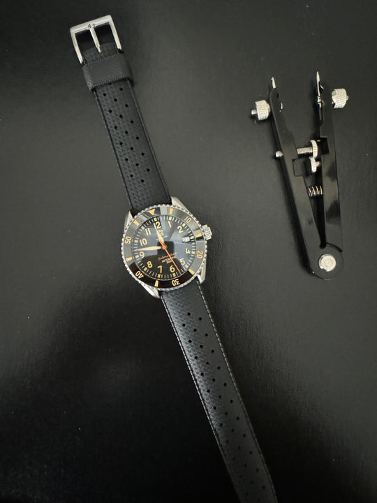 Tropic Bands watch with black perforated strap and silver buckle, dark dial
