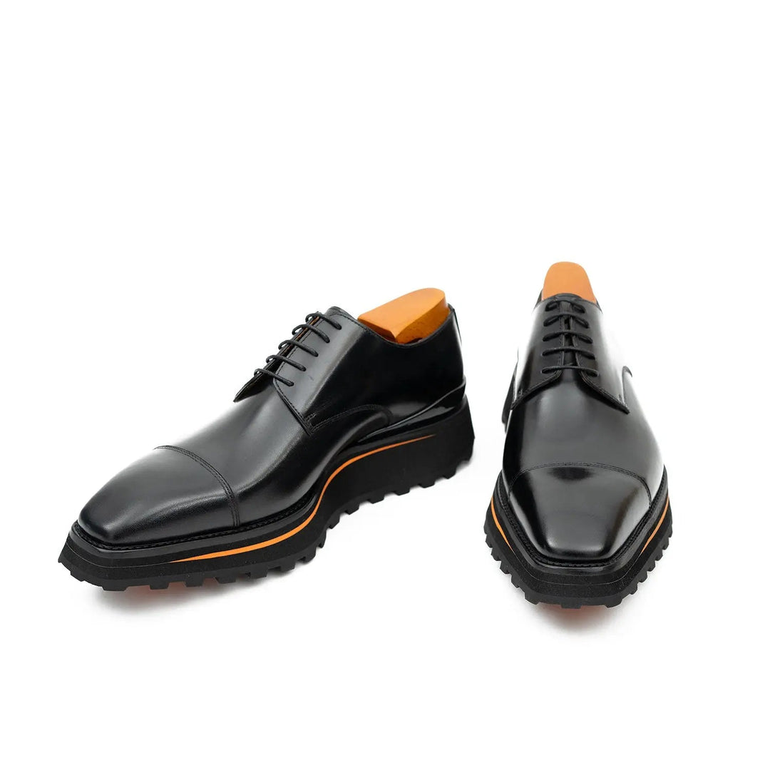 Black derby shoes front view with orange-lined platform and chunky rubber tread