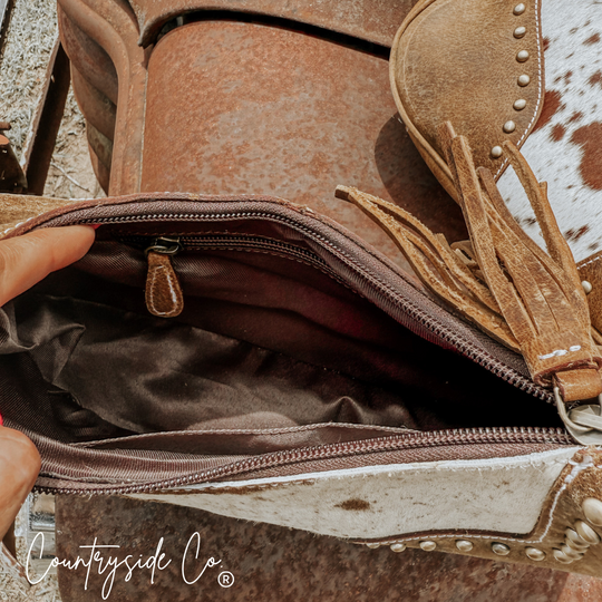 Interior view with zipper track and leather trim; fringe tassel at bag opening