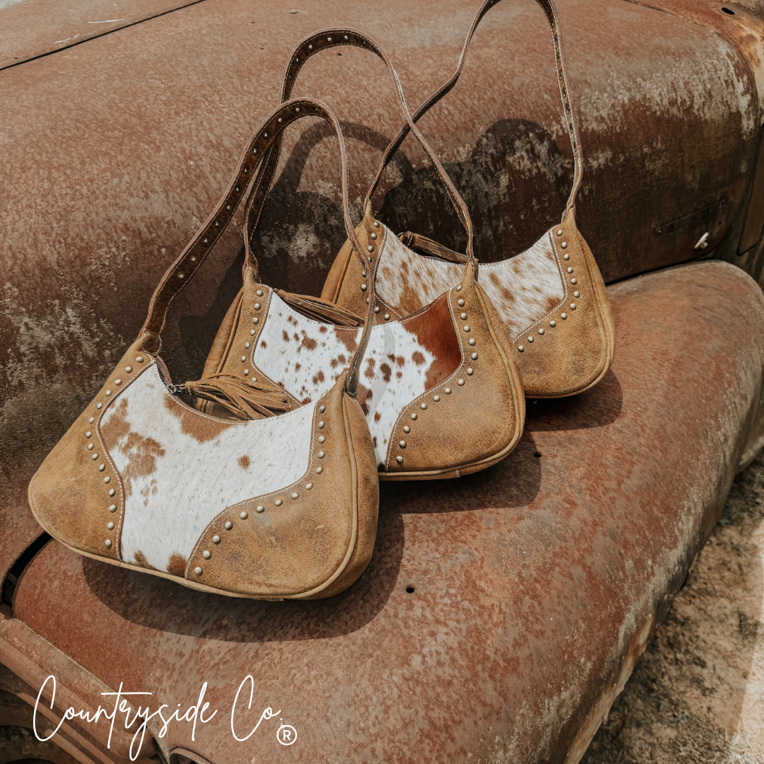 Cowhide leather handbags with fringe trim and metal-studded saddles on both sides