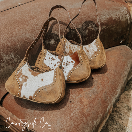 Cowhide leather handbags with fringe trim and metal-studded saddles on both sides