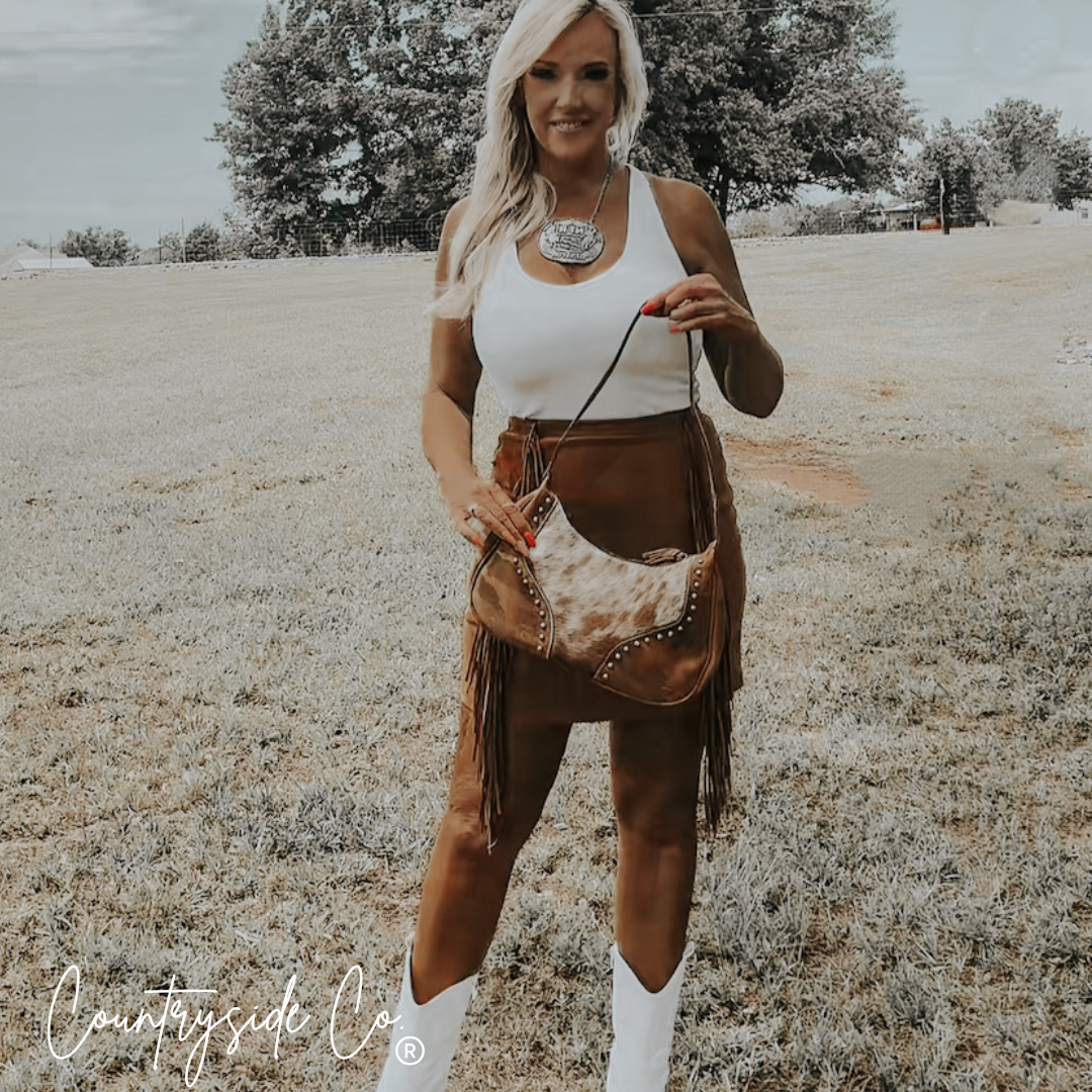 Cowhide leather crossbody handbag with fringe, metal studs, and adjustable strap