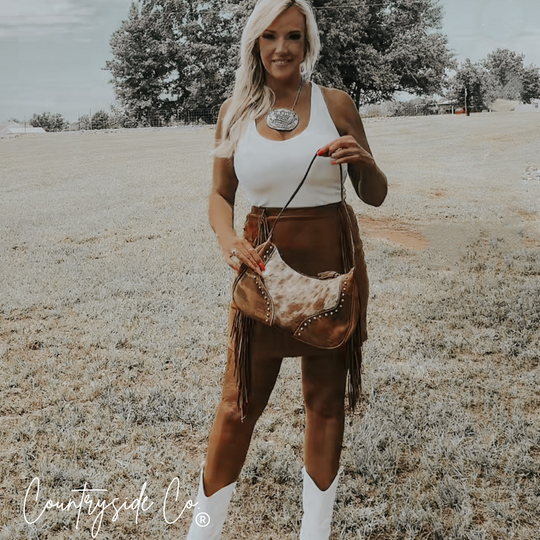 Cowhide leather crossbody handbag with fringe, metal studs, and adjustable strap