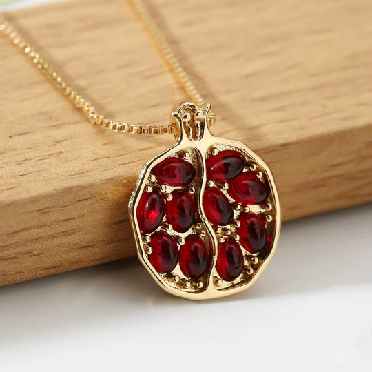 Red gemstone pomegranate pendant on gold-tone chain with small crown detail