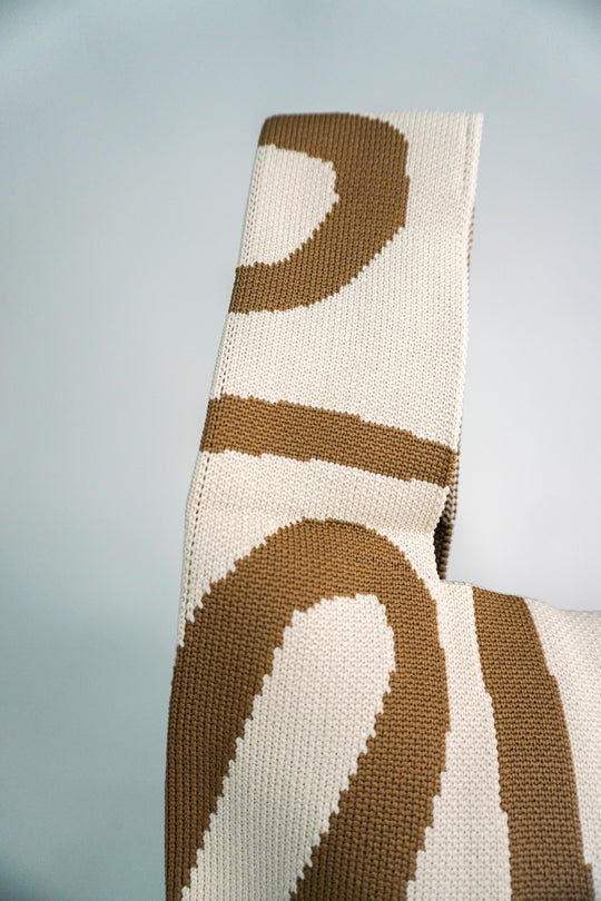 Close-up meander knit pattern on beige handbag