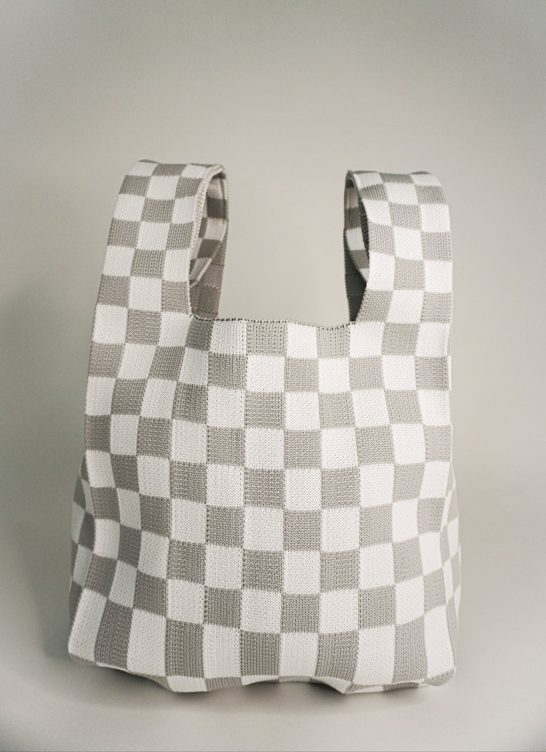 Checkered tote-style handbag with wide strap openings, grey and white