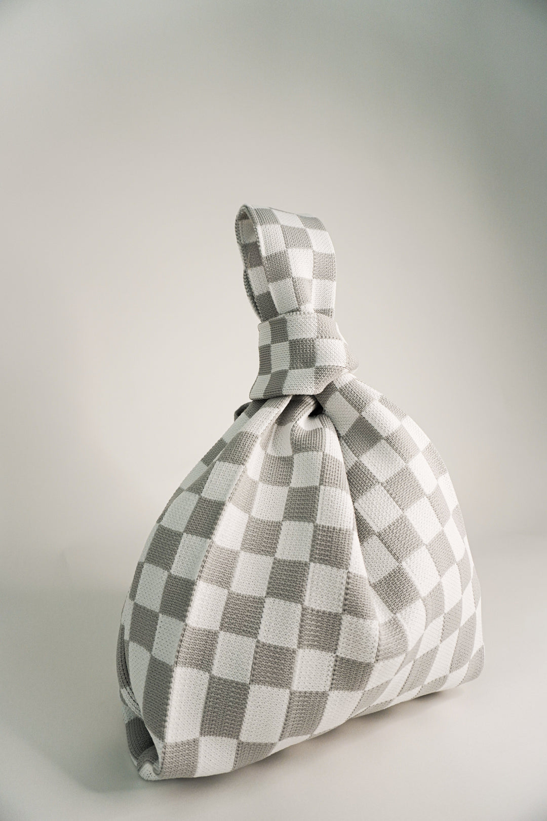 Grey-and-white checkered handbag with gathered fabric base and short drawcord