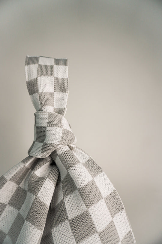 Close-up of grey-and-white checkered drawstring tie on the handbag