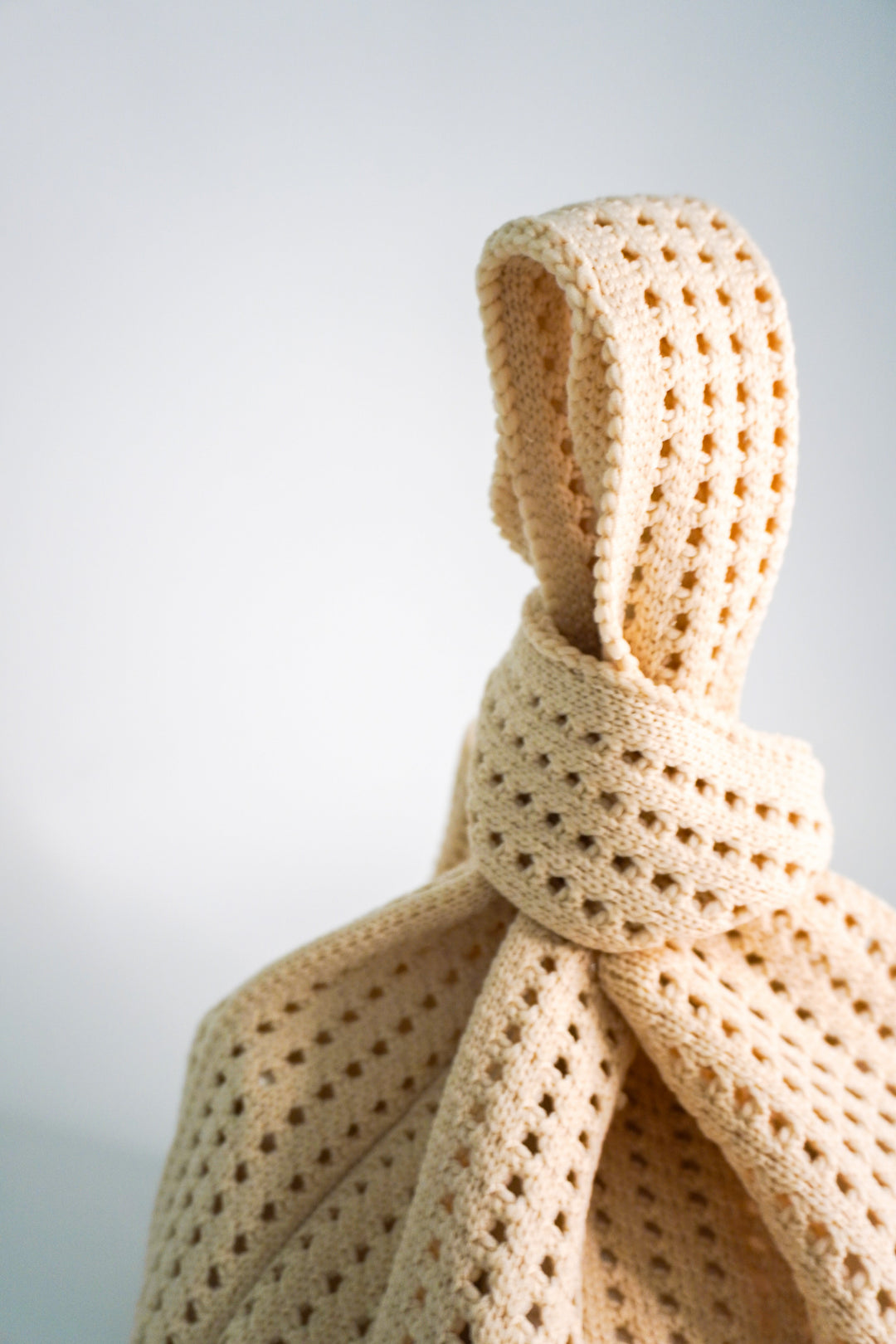 Crochet handbag close-up of the wrapped drawstring tie and openwork lattice stitch.