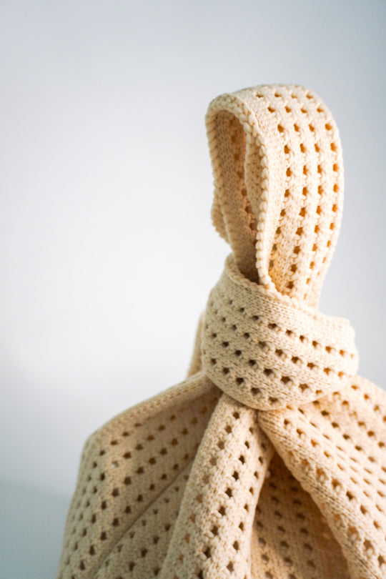 Crochet handbag close-up of the wrapped drawstring tie and openwork lattice stitch.