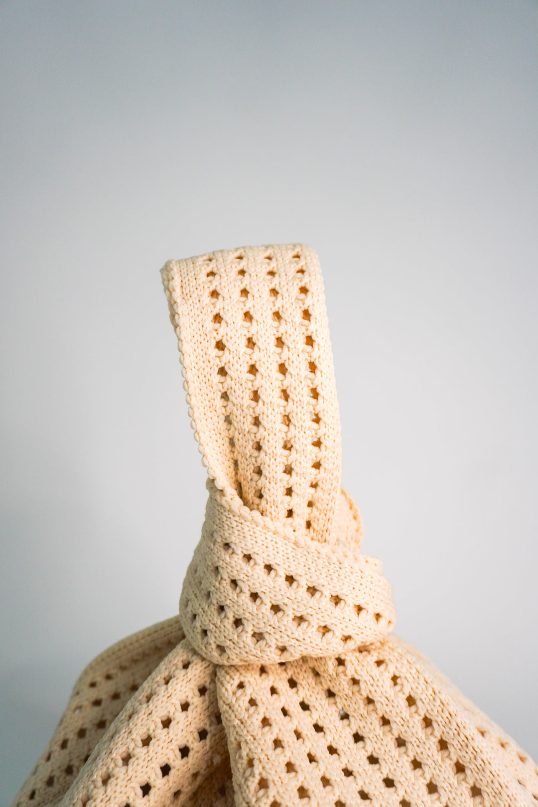 Oat crochet handbag close-up of openwork panel and wrapped tie at the neck.