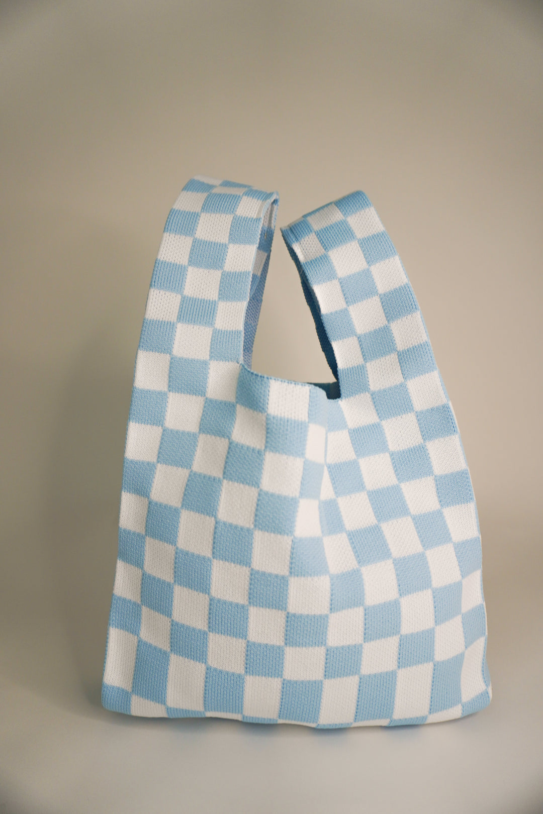 Classic checkered blue handbag side view with stitched top handle opening