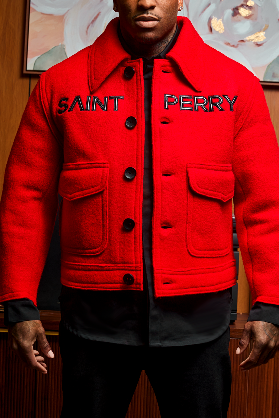 Red sherpa-style jacket front with black SAINT PERRY print and button placket