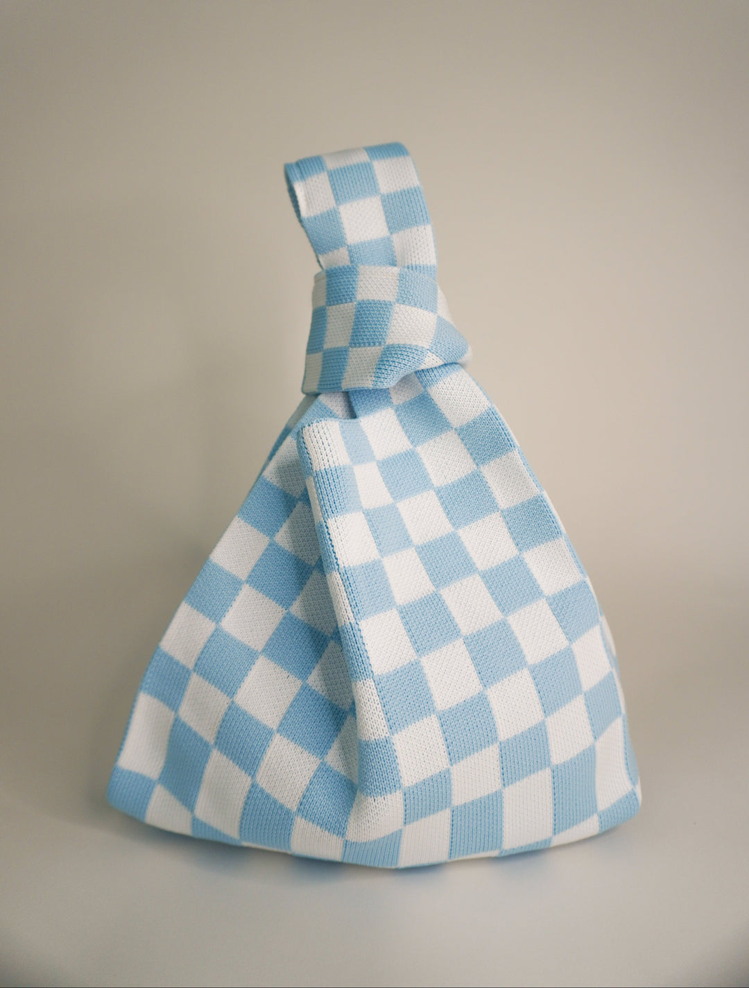 Classic checkered blue handbag with top handle, folded triangular silhouette