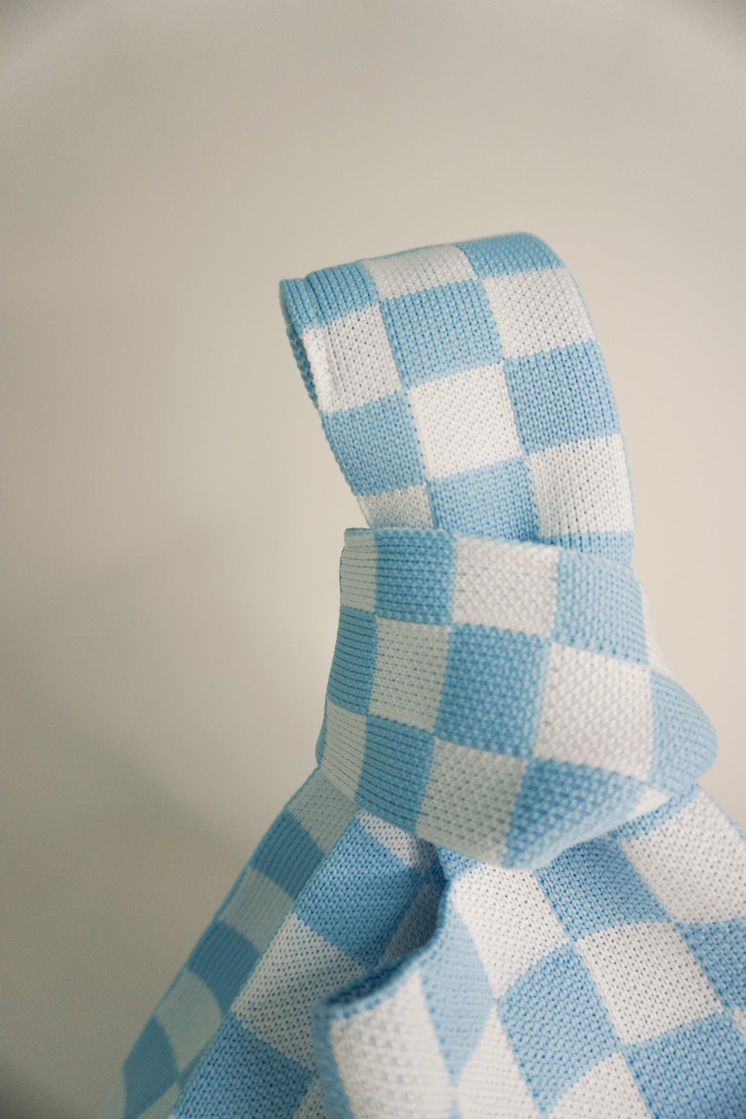 Checkered blue handbag fabric close-up on folded handle seam