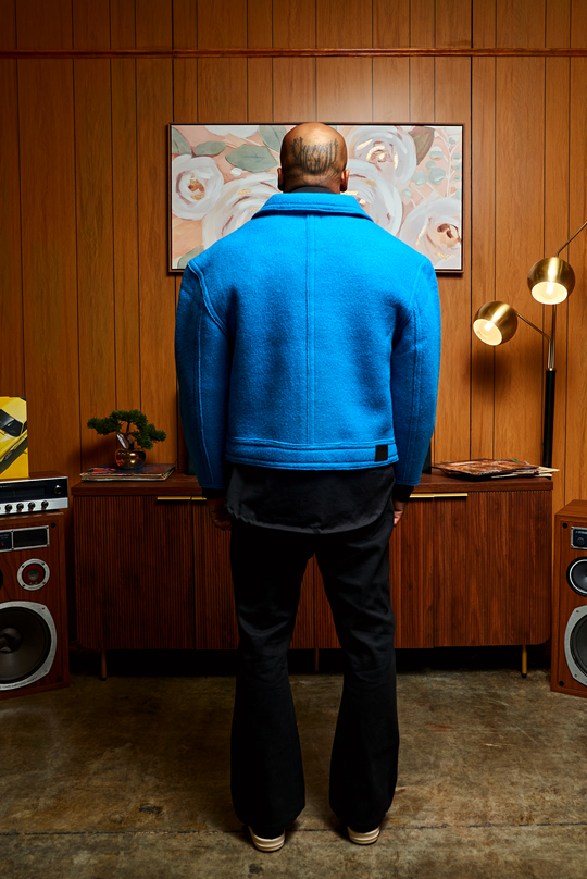 Blue boxy jacket back view: center seam, structured yoke, hem band with tag