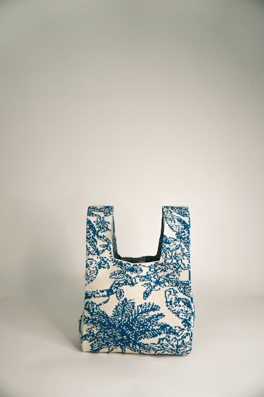 Blue and cream knit handbag with small square body and open U-shaped top.