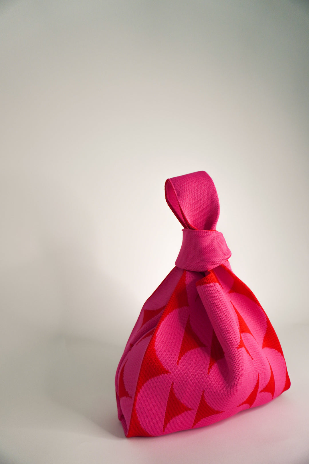 Pink Portobello handbag, angled view with knotted top and floral leaf pattern