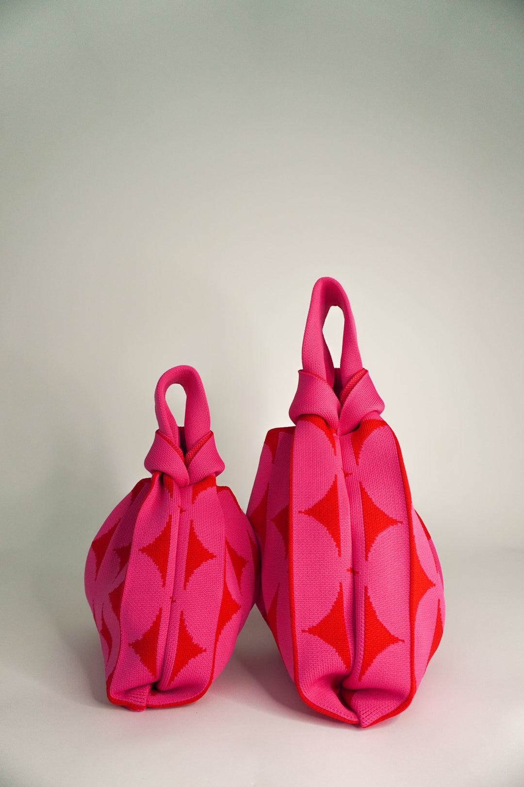 Pink Portobello handbags, side view of two with knotted drawstring tops