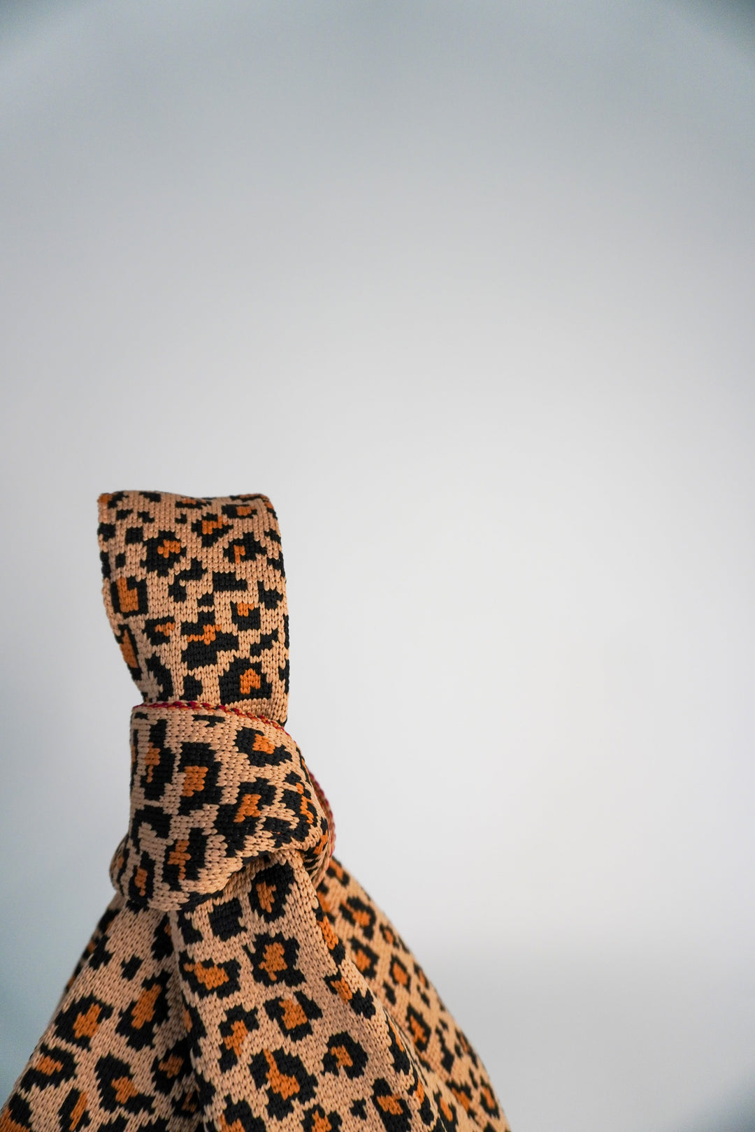 Leopard print top of the handbag with knotted closure and textured woven pattern