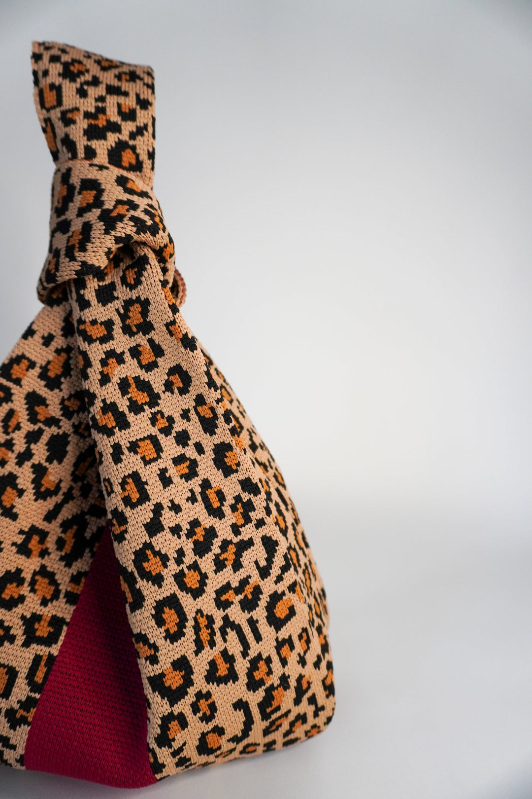 Leopard print side view of handbag with red interior lining panel