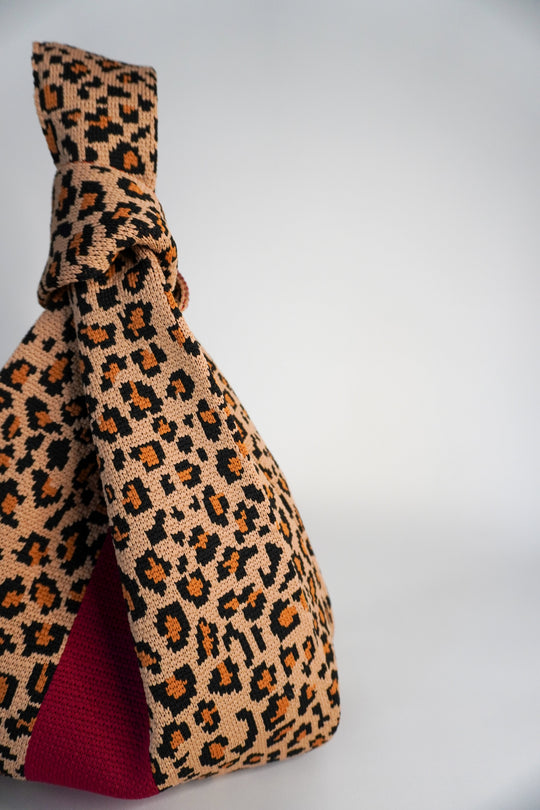 Leopard print side view of handbag with red interior lining panel