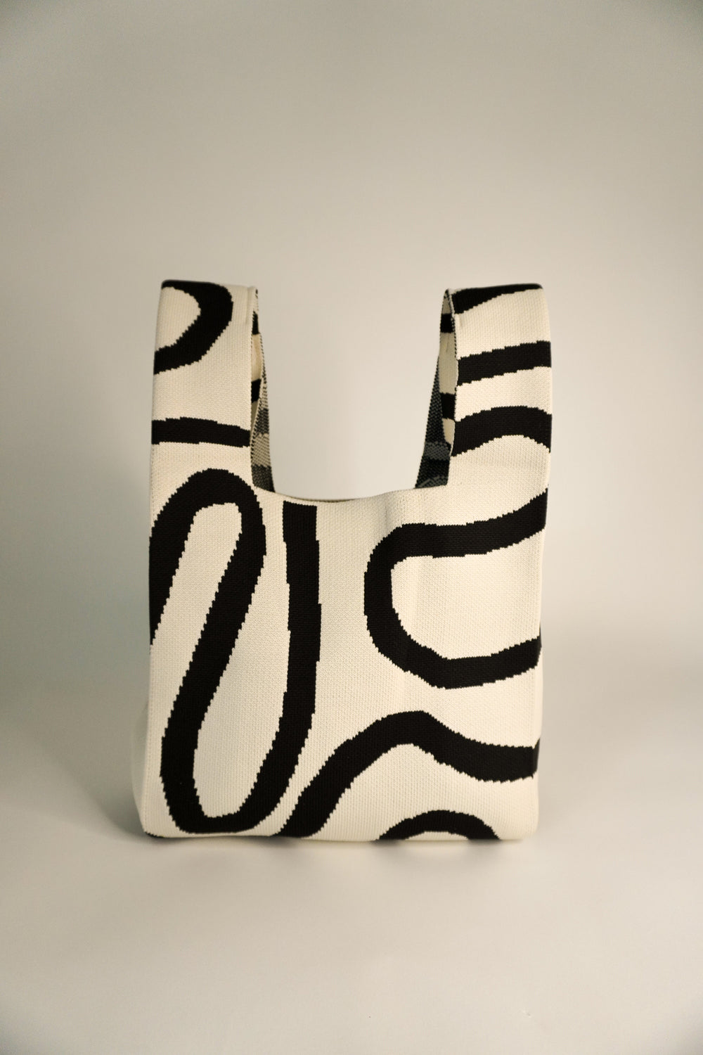 Handbag with wide opening and black-and-cream abstract striped pattern