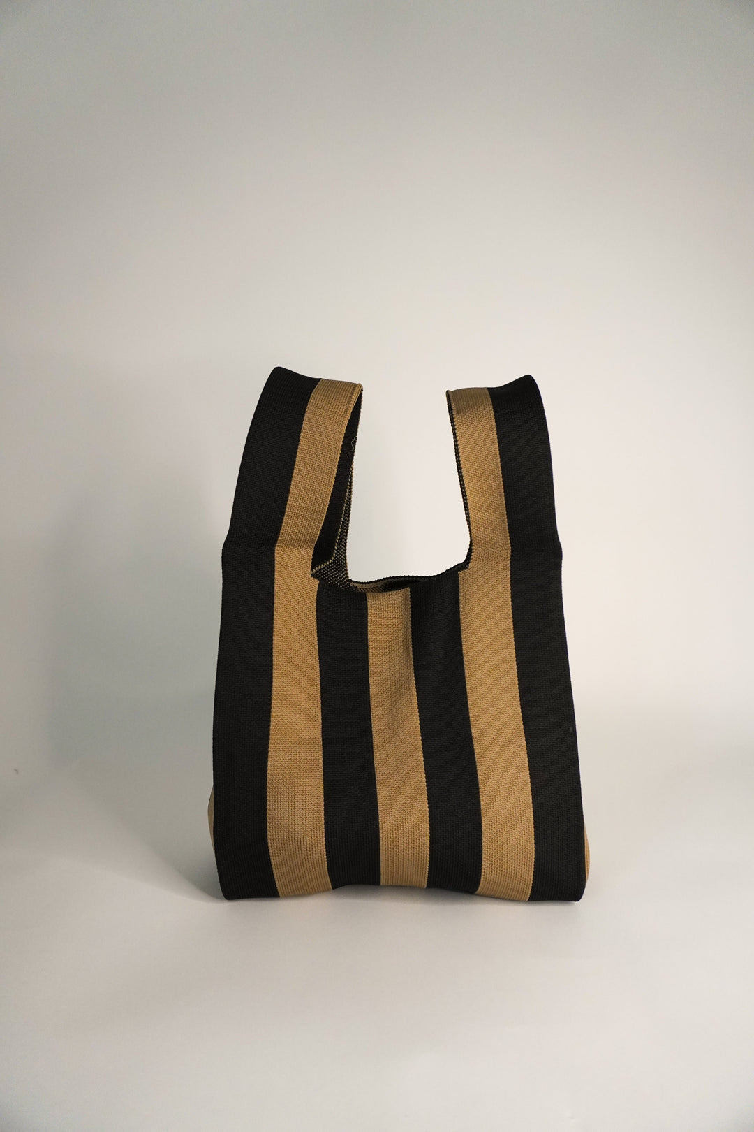 Bolso saco con rayas verticales negro y marrón, cierre superior con botón y abertura en U