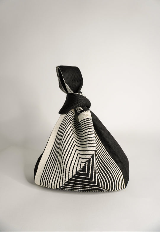 Black hand bag pouch with geometric labyrinth stripes and knotted top handle.