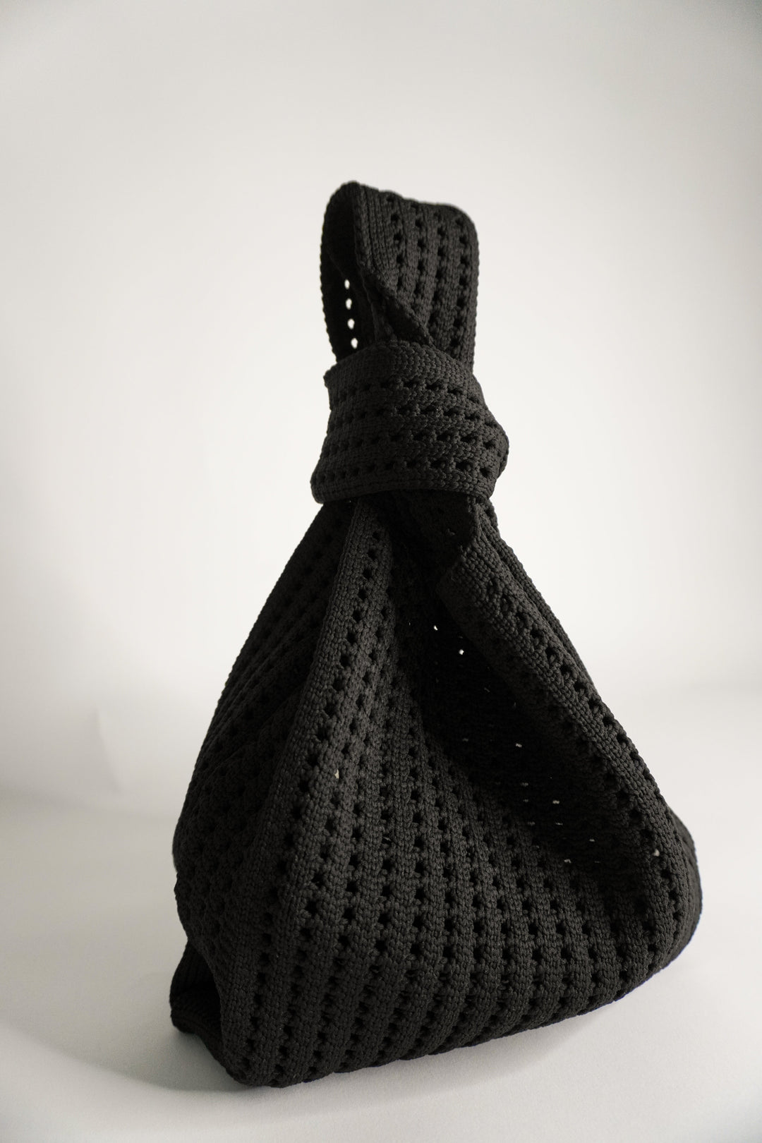 Schwarze Häkelhandtasche mit gedrehtem Knoten oben und geräumigem Beutel