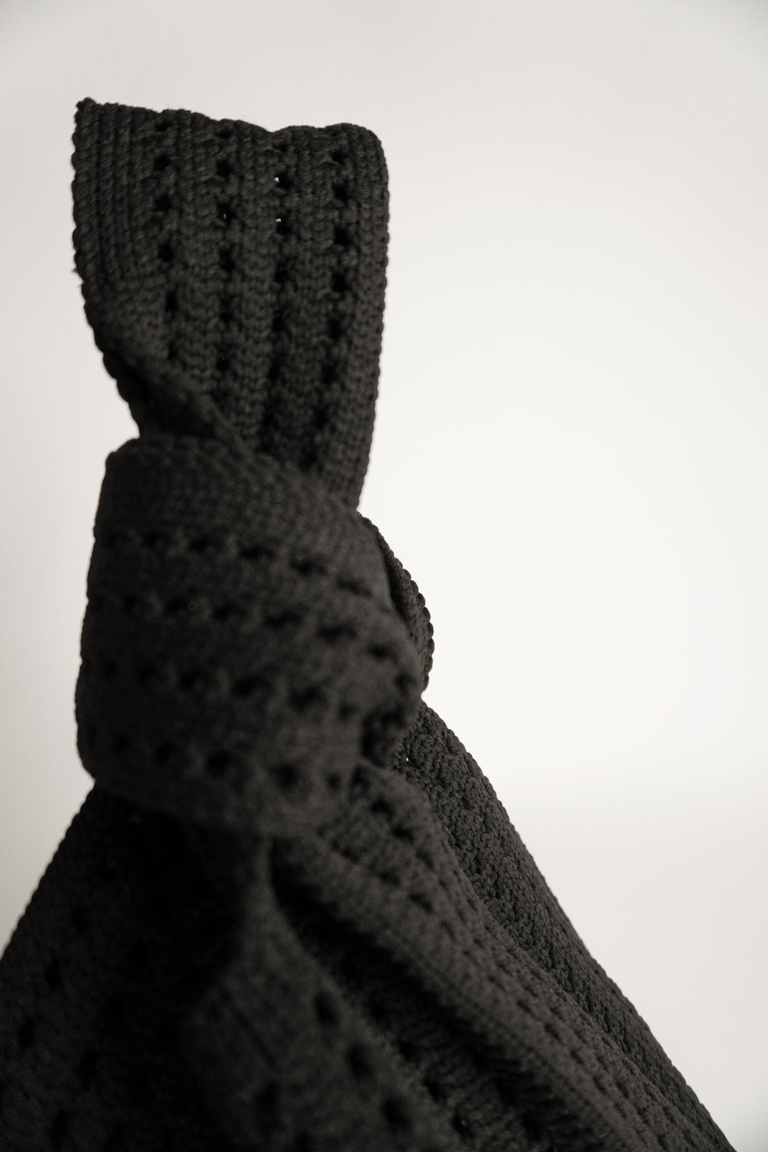 Detailansicht: schwarze Häkelmaschen und Schlinge am Knoten der Handtasche