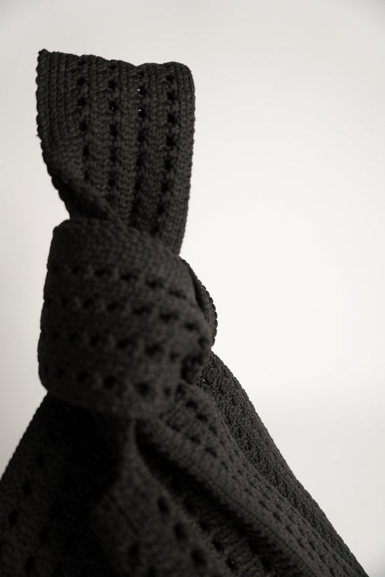 Detailansicht: schwarze Häkelmaschen und Schlinge am Knoten der Handtasche