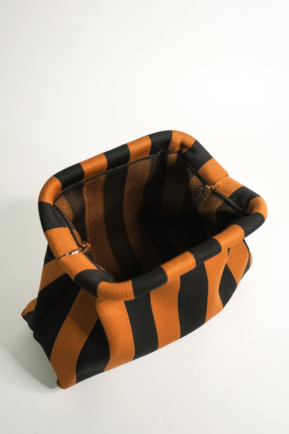 Brown-and-black striped clutch bag interior view, folded top opening