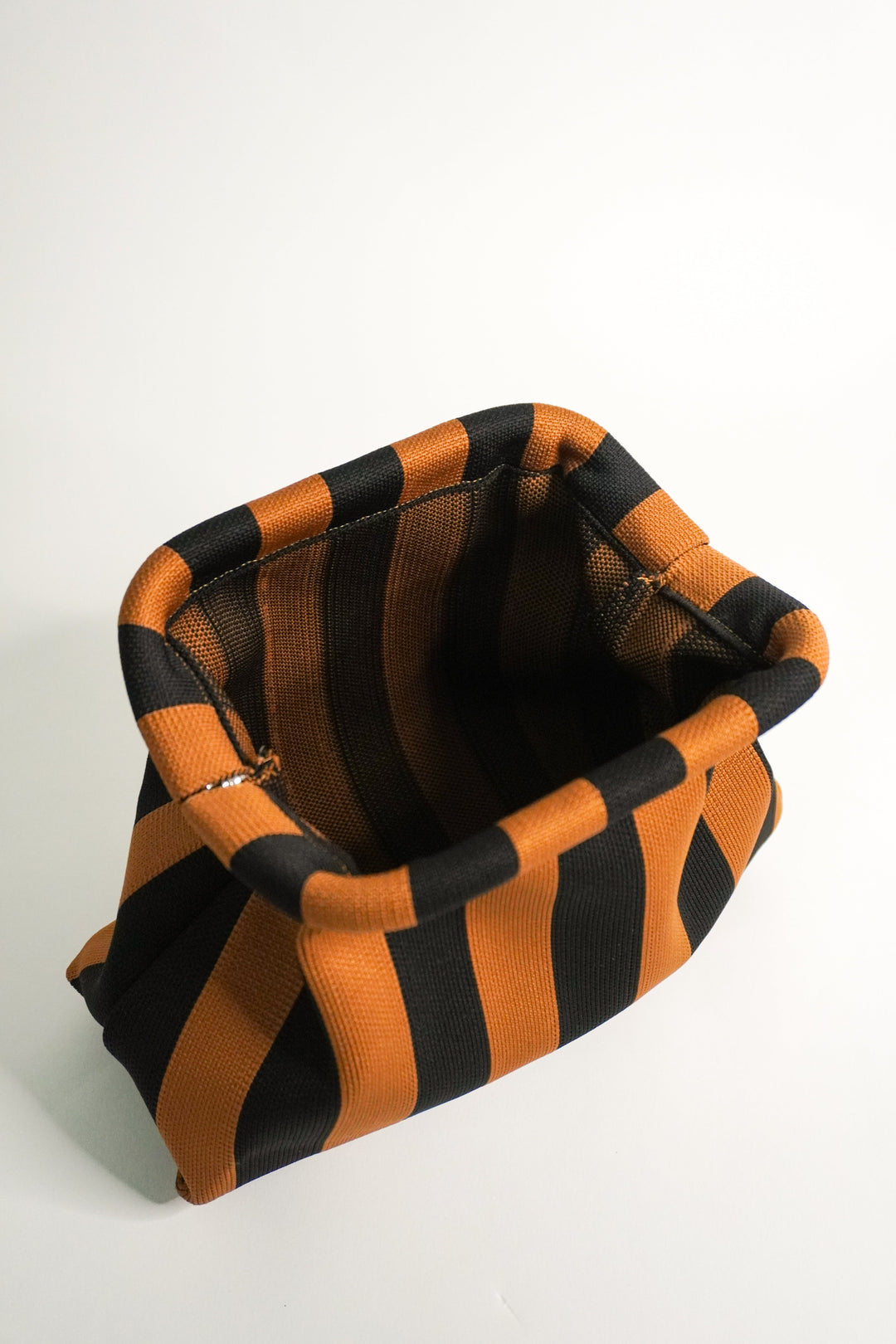 Brown-and-black striped clutch bag interior view, folded top opening