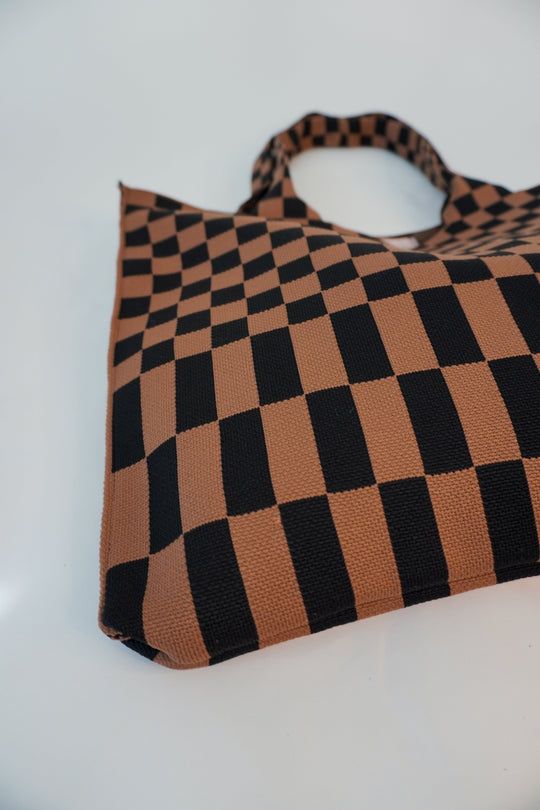Close-up of checkered skinny tote with brown and black squares and striped bottom edge.