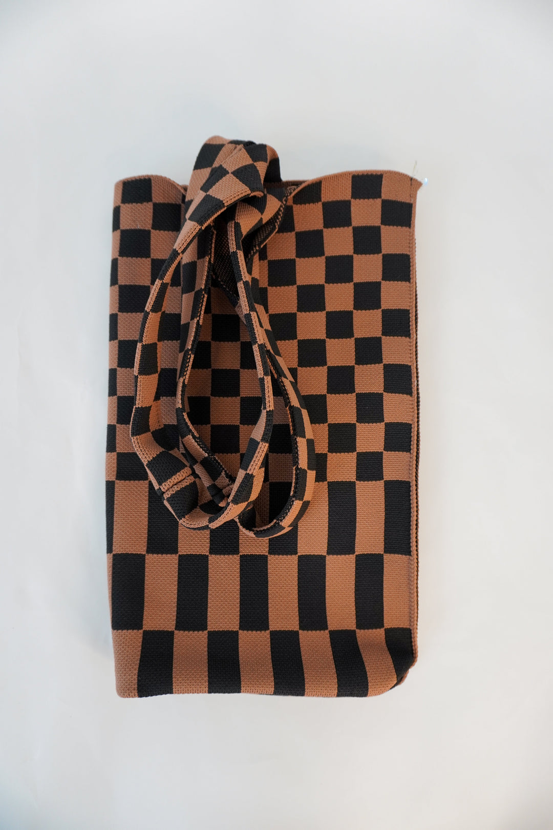 Skinny tote bag with checkered brown-and-black squares and long tied handle detail.