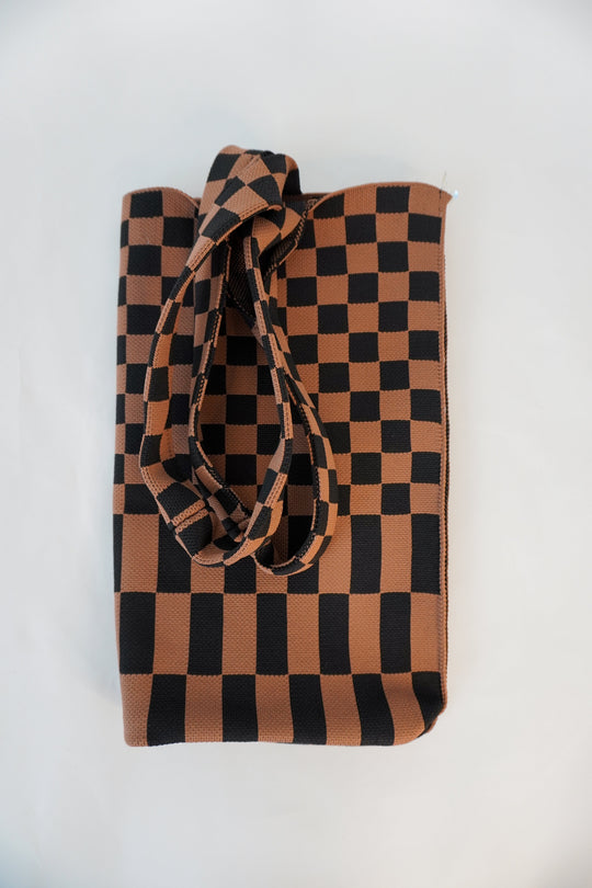 Skinny tote bag with checkered brown-and-black squares and long tied handle detail.