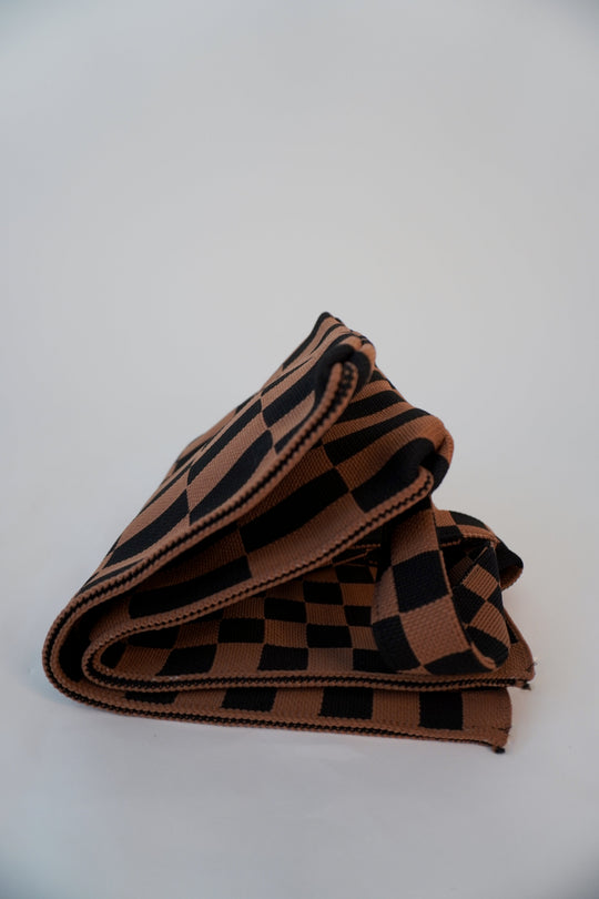 Folded checkered skinny tote with stacked stripes and brown-and-black square pattern.